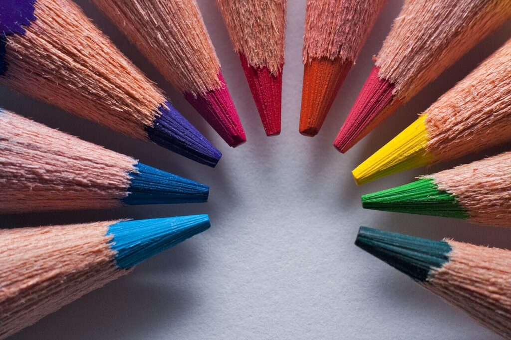 Lápices de colores dispuestos en círculo sobre papel, material para dibujar las tarjetas del cuento.